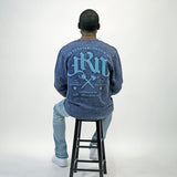 Person wearing a blue acid wash sweatshirt with text on the back, sitting on a black stool against a white background