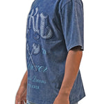 Person wearing a blue acid wash graphic t-shirt with text and design on a white background with text and graphics on the front Juren logo battle axe