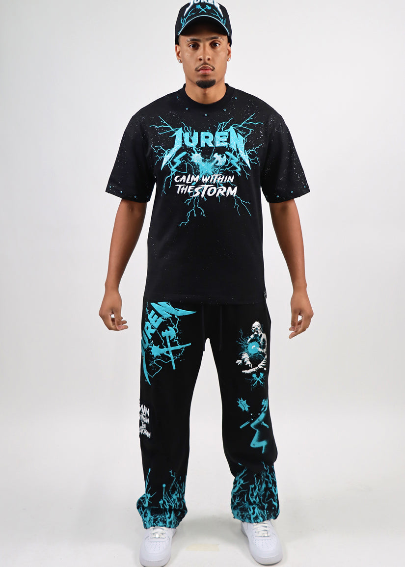 Man wearing a black t-shirt and sweat pants with teal & white graphics on a white background