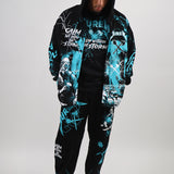 Person wearing a black and teal graphic hoodie and pants set on a white background
