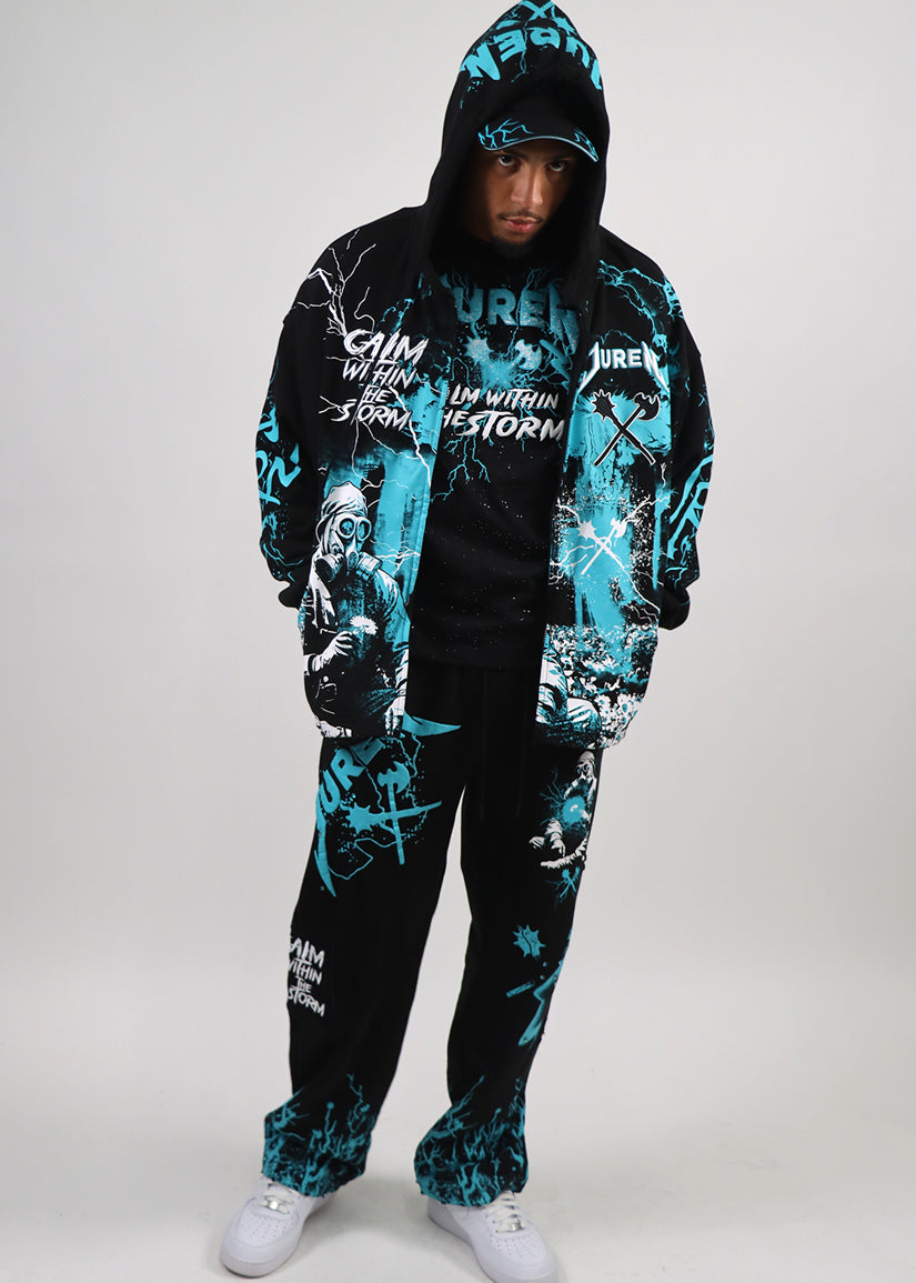 Person wearing a black and teal graphic hoodie and sweat pants set on a white background