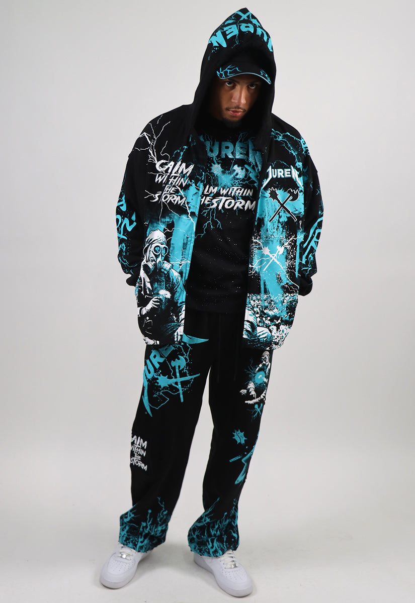 Person wearing a black and teal graphic hoodie and sweat pants set on a white background