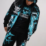 Person wearing a black and teal graphic hoodie and sweat pants set on a white background