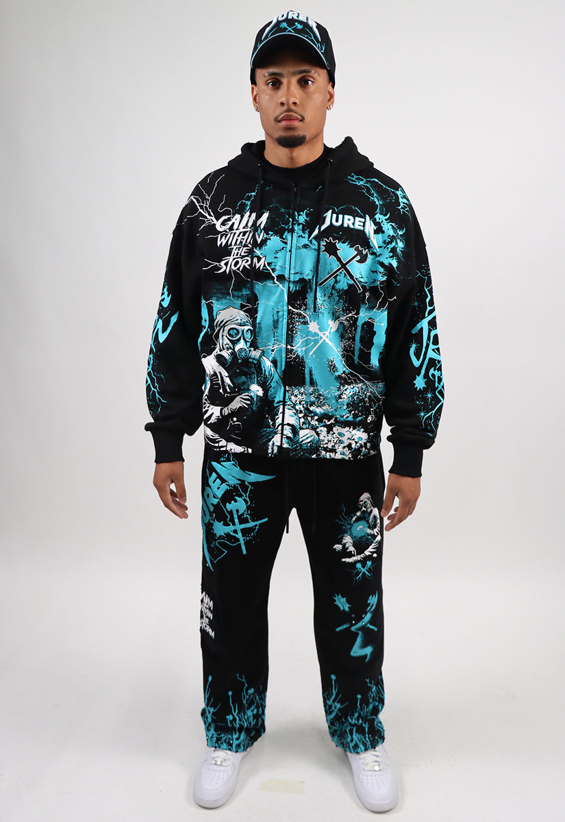 Person wearing a black and teal graphic hoodie and pants set on a white background