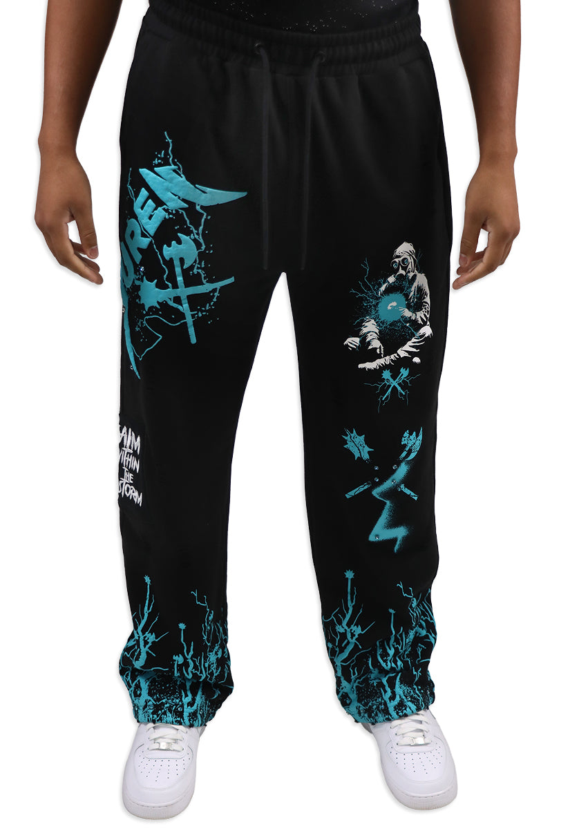 Black sweatpants with teal graphics worn by a person on a white background
