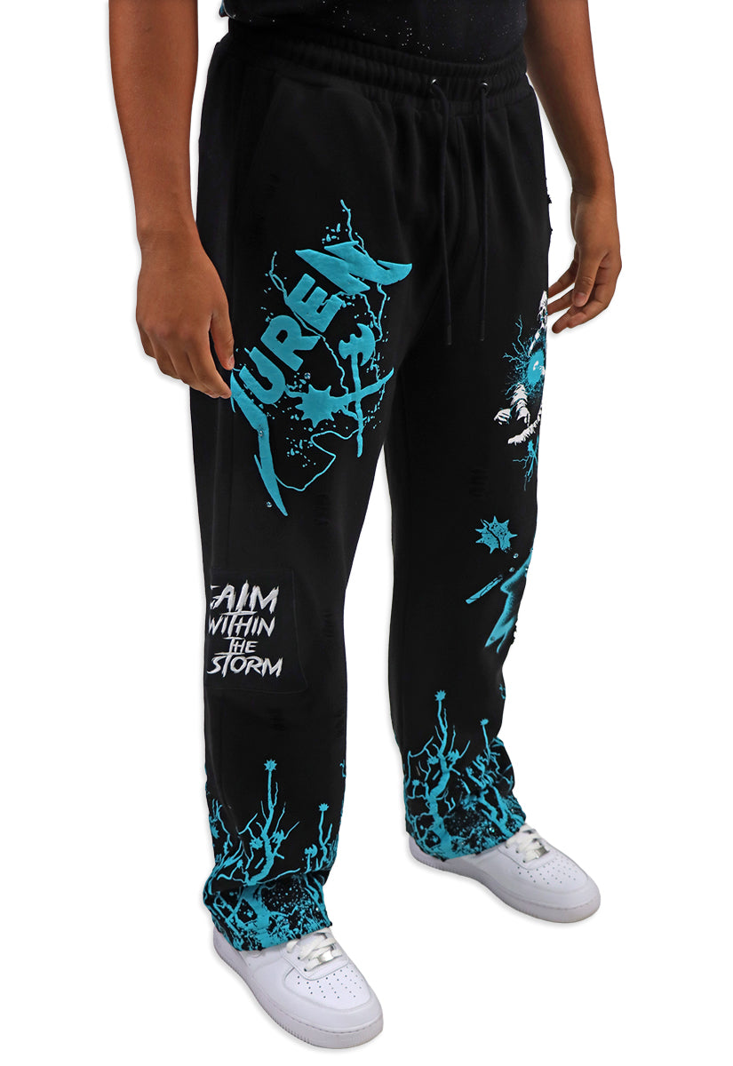 Black sweatpants with teal graphics and text worn by a person on a white background