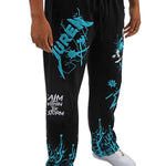 Black sweatpants with teal graphics and text worn by a person on a white background