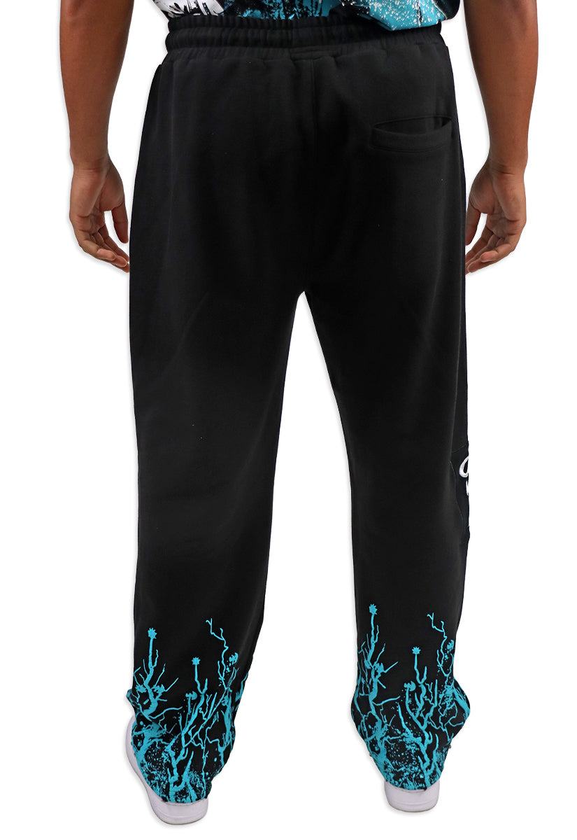 Black pants with teal designs on the cuffs worn by a person on a white background