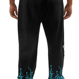 Black pants with teal designs on the cuffs worn by a person on a white background