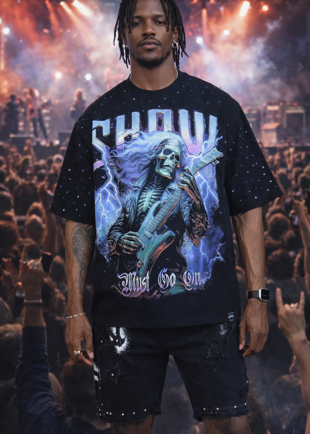 Person wearing a black t-shirt with a graphic design in front of a concert crowd.