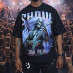 Person wearing a black t-shirt with a graphic design in front of a concert crowd.